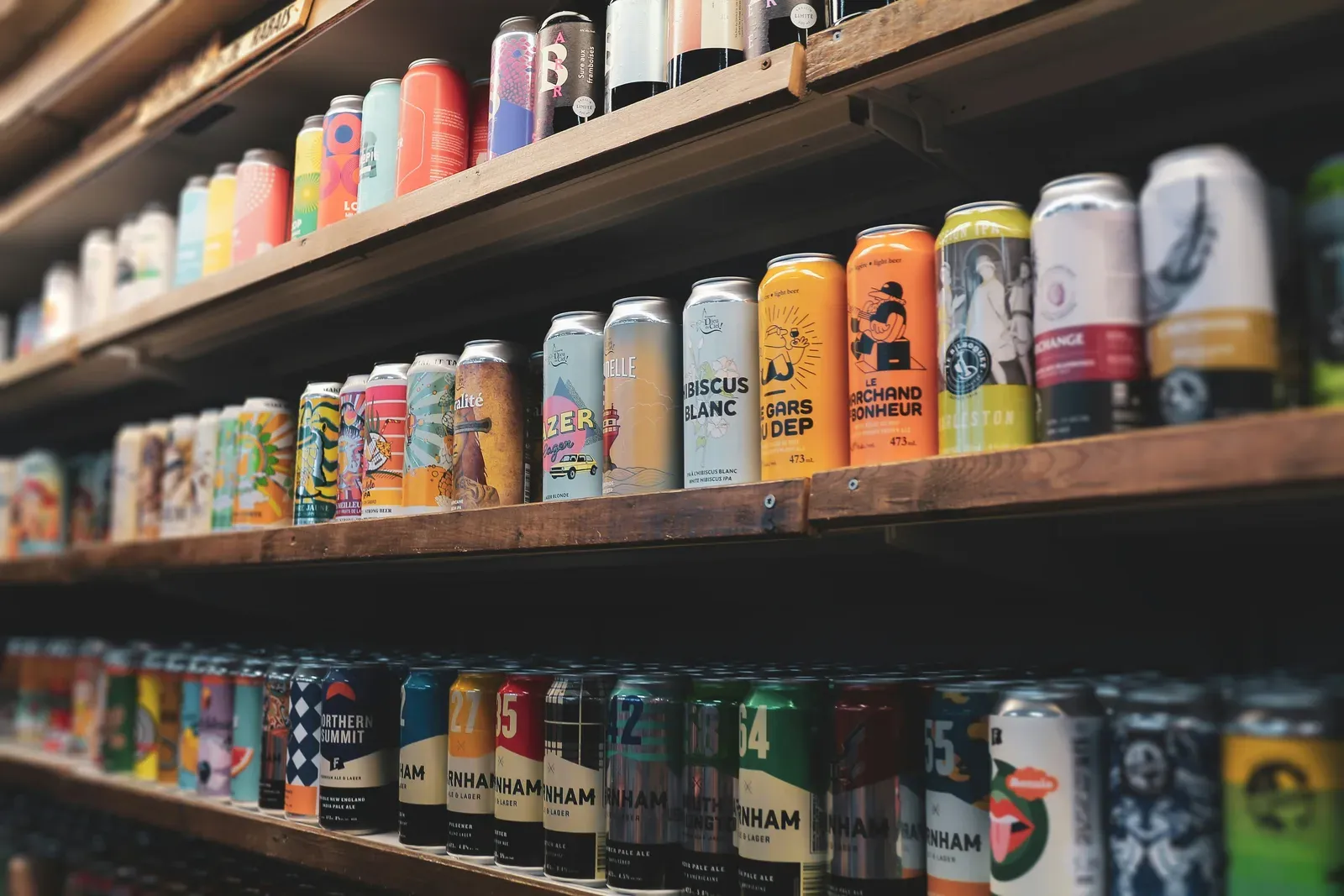 Cans of beer arranged on wooden shelves.
