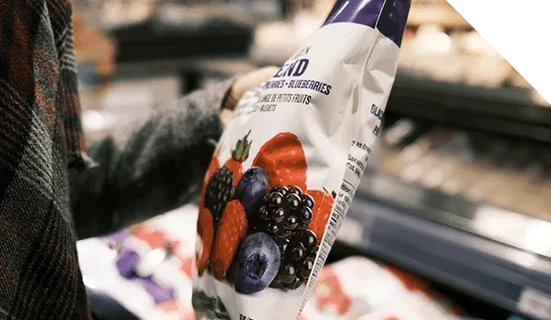 A shopper holding a bag of frozen berries.